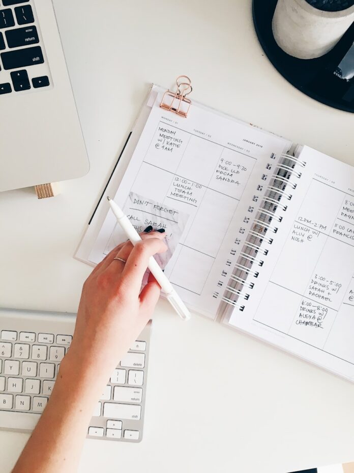 Photo by Marissa Grootes person holding notepad and pen flat lay photography