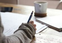 재무덕후가 알려주는 경제와 친해지는 방법 person writing on brown wooden table near white ceramic mug